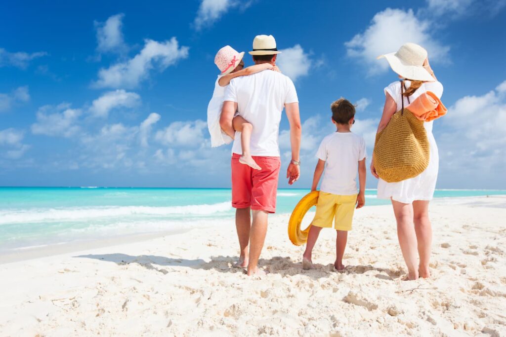 Familienurlaub Pauschalreise - Familie spaziert an Traumstrand